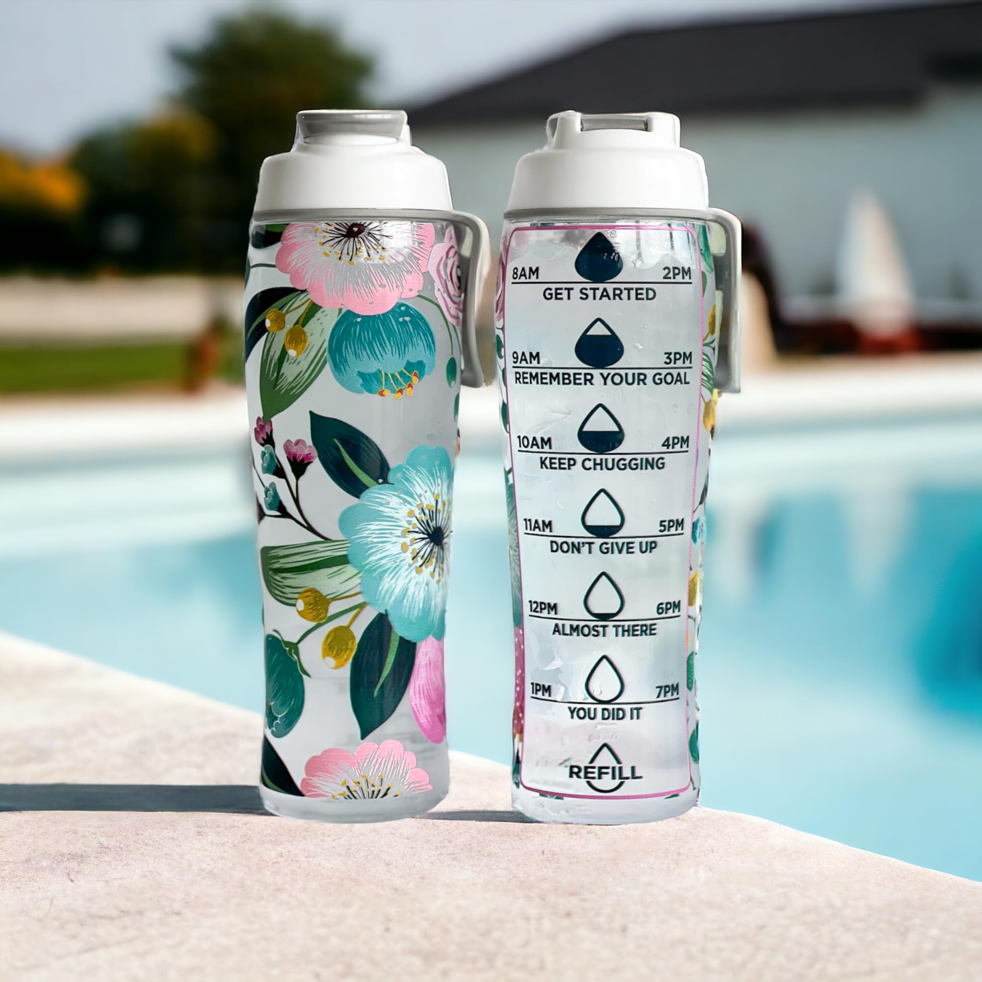 Two water bottles with floral design and motivational text by a pool.