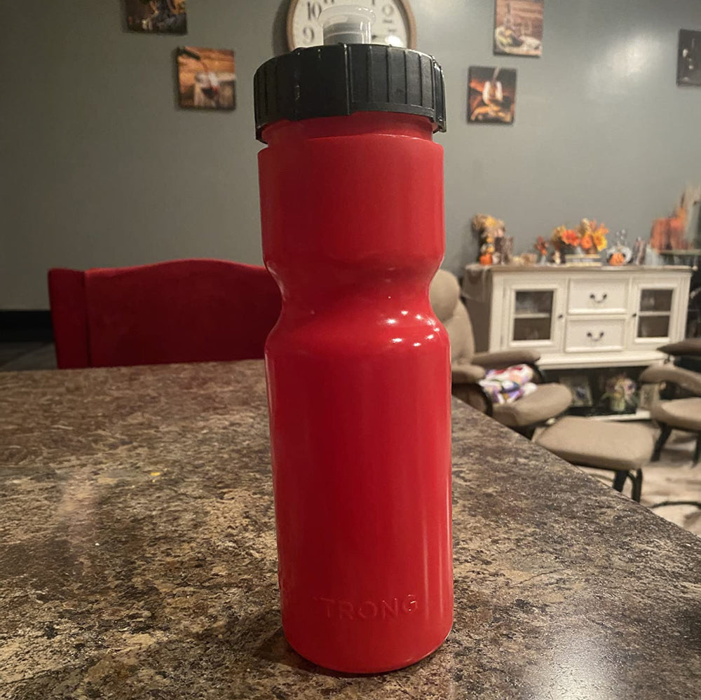 Red water bottle with black top on a kitchen counter